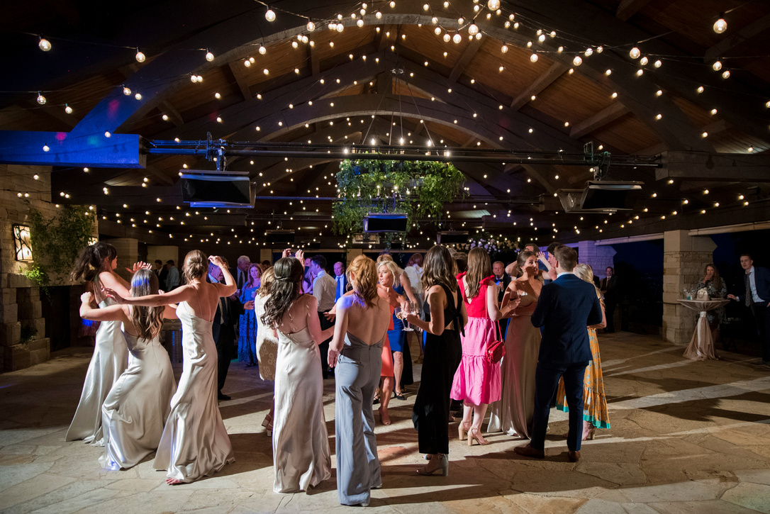 A group of people dancing at a wedding reception with twinkle lights at The Sanctuary wedding venue.