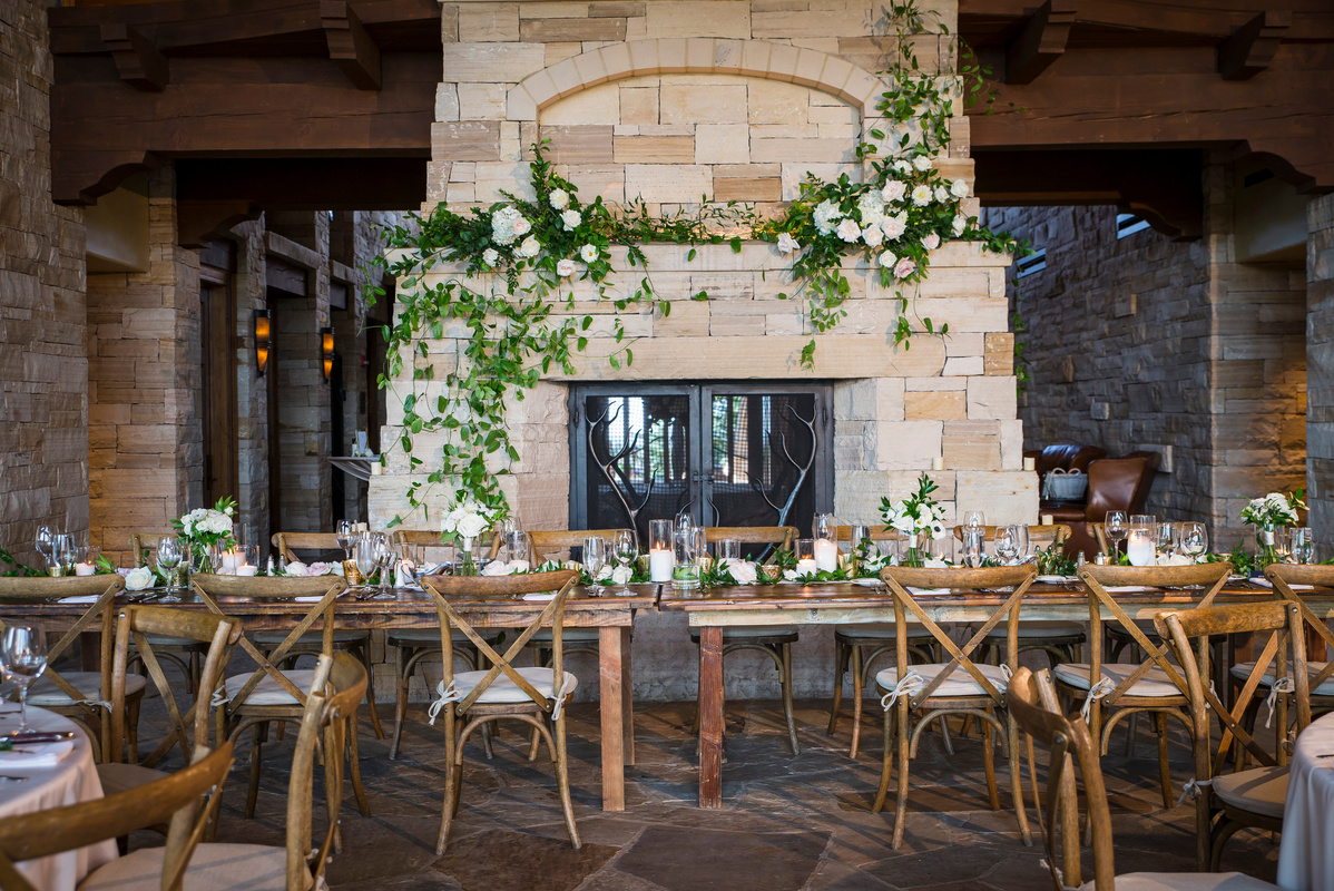 Tables and chairs set up in front of a stone fireplace for a wedding reception at The Sanctuary in Sedalia, Colorado.