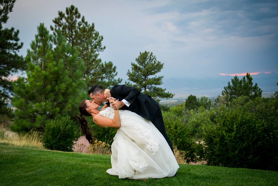 A bride and groom kiss in front of the mountains.